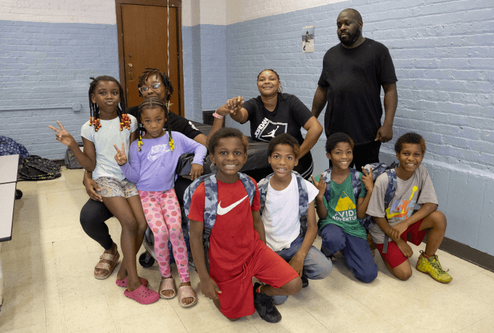Children and volunteers gathered together, smiling after a community meal
