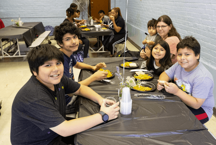 Children smiling around a table as they share a hot meal together